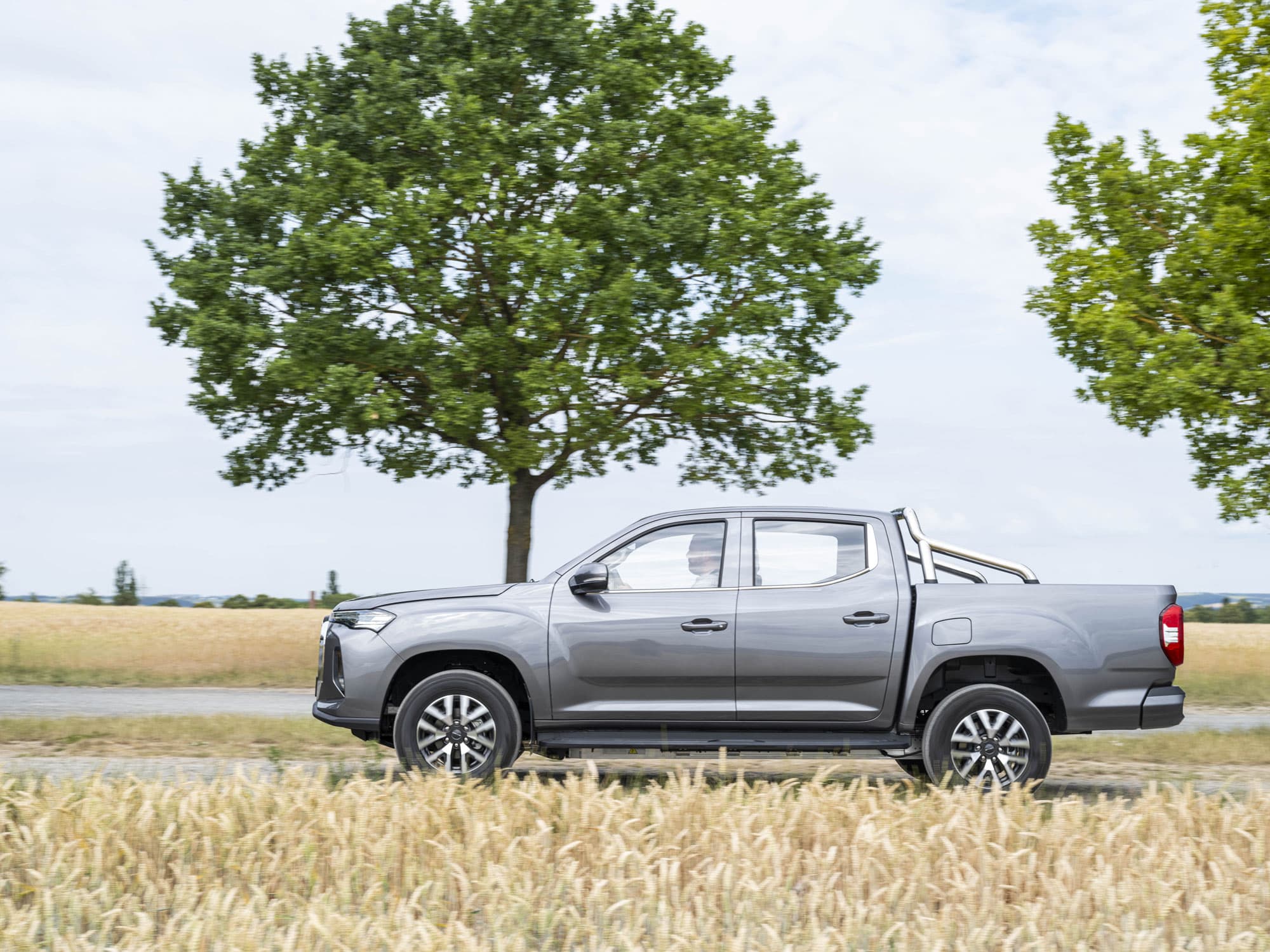 Maxus T90 EV Grijs zijaanzicht tussen velden